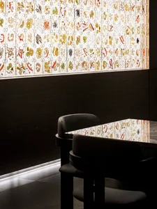 A modern restaurant setting with a glass window featuring intricate patterns and colorful illustrations.