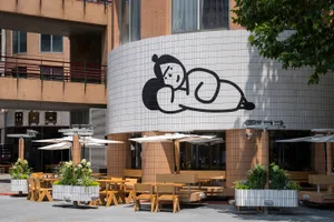 Exterior of a cafeteria featuring a tile and concrete design with a large mural of a cartoon character.