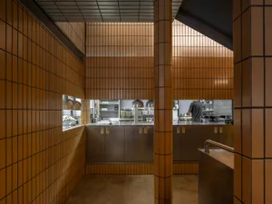A spacious, industrial-style restaurant kitchen with concrete walls, metal countertops, and a minimalist design.