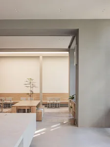 Modern cafeteria space with wooden tables and chairs, minimalist design, and natural light.