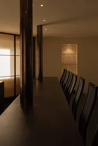 A sleek, modern restaurant bar featuring wooden columns, illuminated by recessed lighting.
