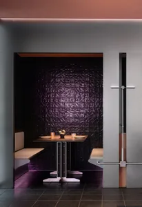 A modern restaurant dining booth with dark tiles and metallic elements.