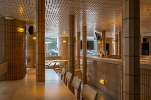 Interior view of a modern restaurant featuring tiled walls and wooden furniture.