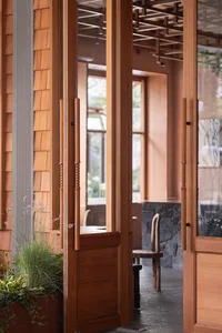 Modern retail shop entryway featuring wooden doors and light fixtures.