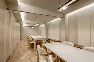 Modern conference room with wooden tables and chairs, paper walls.