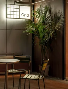 A modern cafe interior featuring metallic accents and a tropical plant.