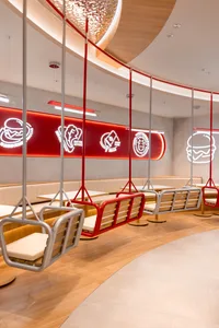 A minimalist restaurant interior featuring modern swing benches made of metal.