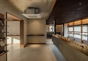 Modern retail store with minimalist design, concrete and wood surfaces, and products displayed on black shelves.