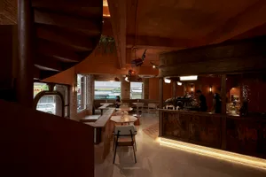 Industrially designed cafe interior featuring concrete and brick walls, wooden ceiling beams, and spiral staircase.