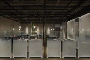 A sleek modern restaurant interior with glass walls and ceiling