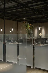 A modern restaurant interior with glass and concrete surfaces, featuring minimalist decor and a spacious layout.
