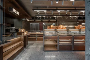 Interior of an industrial-style bakery with brick, concrete, and wooden materials.