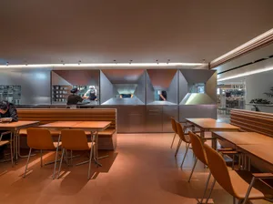 Industrial-style restaurant kitchen with metal tiles and open seating area.