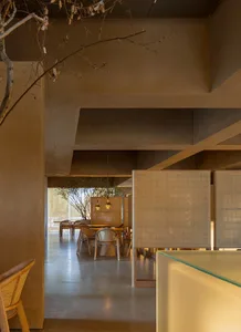 Interior of a minimalist restaurant featuring concrete and woven materials.