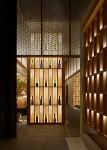 Modern bar interior with illuminated shelves displaying bottles and a patterned ceiling.