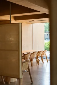Modern restaurant seating area with cane-backed chairs and wooden tables.