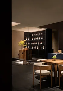 Modern restaurant interior with wooden furniture and shelves showcasing various objects.