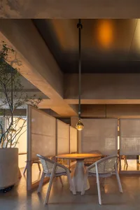 Interior view of a restaurant featuring woven fabric panels and concrete walls.