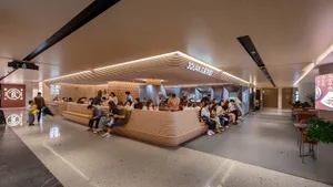 A modern food court with a desk made of wood for customers to eat and sit