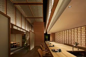 A minimalist restaurant interior with a wooden counter and seating.
