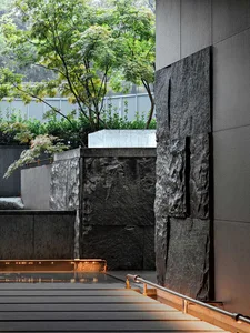 Urban water feature with black stone wall and greenery