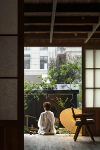 A traditional oriental interior designed with wooden elements and paper screens, featuring a person sitting in a wooden chair
