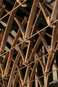 Detailed view of industrial architectural framework composed of wooden beams and metal rods.