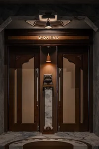 Industrial-style bar entrance with wooden doors, cane panels, and marble accents.
