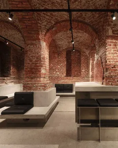 Interior Design of an Industrial Restaurant Bar Featuring Exposed Concrete Walls, Arched Stone Columns, and Bench Seating wit