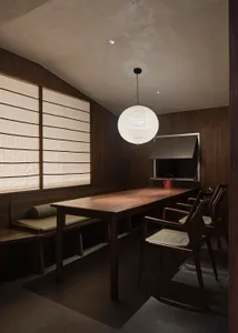 Industrial-style restaurant with a hanging ceiling lamp and wooden furniture, featuring a large window with curtains and a te