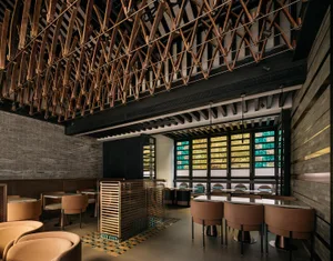 An industrial-themed restaurant interior with wooden structures and concrete walls, featuring glass elements for lighting and
