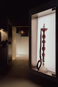 A sophisticated glass hookah displayed in a white-lit, framed showcase.