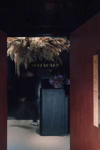 A minimalist interior with black wooden furniture and pampas grass decorations.