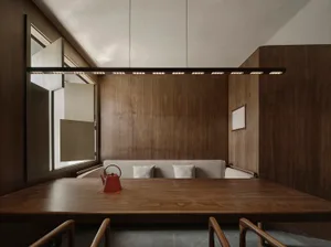A minimalist interior with wooden walls and a wooden table, featuring a red teapot as a centerpiece.