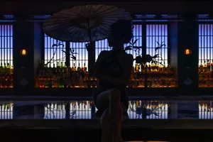 Modern cocktail bar with glass walls and bottles in the background.
