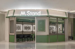 Modern coffee shop storefront with green accents and white text.