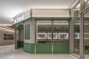 A modern coffee shop storefront with a white and green color scheme, featuring a glass front and metallic accents.