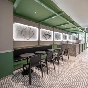 A modern coffee shop interior with green accents and wooden seating.
