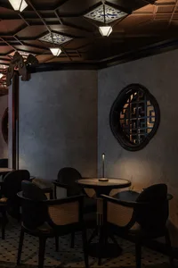 A modern restaurant interior featuring wooden furniture, porcelain tableware, and fabric seating.