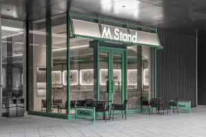 A modern retail storefront with glass walls and green accents.