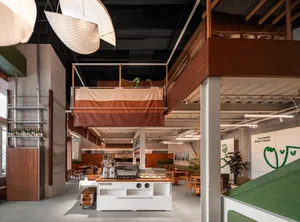 A spacious, industrial-style cafe interior featuring a wooden counter and seating area
