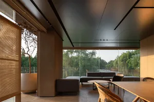 A modern minimalist living room with concrete walls and floor, framed by a large glass window overlooking a serene outdoor la