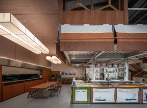 A modern commercial kitchen with wooden elements and a long table.