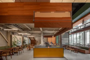 Interior view of a modern restaurant/cafe with wood accents and open seating areas.