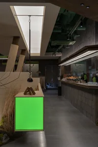 Modern interior design of a restaurant with a green screen counter and contemporary materials.