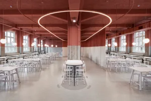 An empty, industrial-style cafeteria with white tables and chairs, concrete flooring, and circular lighting fixtures.