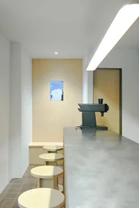 Minimalist coffee shop interior featuring concrete flooring and seating area.