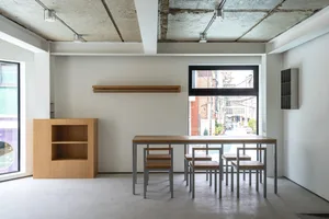 A minimalist office space featuring a wooden table and chairs, metal legs, and minimalist design elements.
