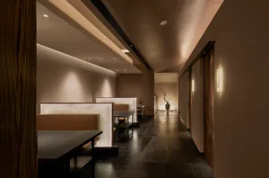 A minimalist restaurant interior featuring stone, leather, and wood materials.