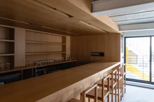 A modern bar counter space featuring a wooden finish with stools and a sink.